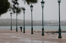 Πολίτης με ομπρέλα περπατά στη βροχερή παραλία της Θεσσαλονίκης