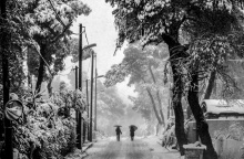 Χιονισμένο τοπίο και δύο πολίτες περπατούν κρατώντας την ομπρέλα τους