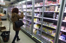 Γυναίκα μπροστά από ψυγείο σούπερ μάρκετ με γαλακτοκωμικά προϊόντα