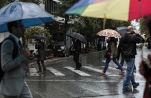 Πολίτες με ομπρέλες προστατεύονται από τη βροχή