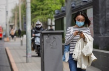 Γυναίκα με μάσκα προστασίας από τον κορωνοϊό περπατά σε δρόμο του Πεκίνου