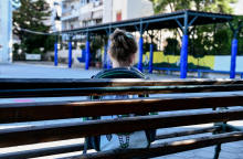 Μαθήτρια Δημοτικού με την τσάντα τους ώμους κάθεται σε παγκάκι στο προαύλιο του σχολείου