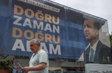 Προεκλογική αφίσα του Ρετζέπ Ταγίπ Ερντογάν σε δρόμο της Τουρκίας και πολίτης που περνά μπροστά από αυτή, κρατώντας την εφημερίδα του