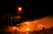 Φλεγόμενο λεωφορείο και πυροσβέστες που επιχειρούν για την ολοκληρωτική κατάσβεσή του