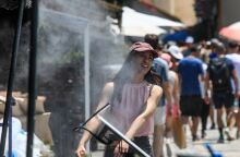 Κοπέλα περνά μπροστά από ανεμιστήρα που ψεκάζει νερό