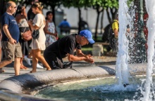 Άνδρας δροσίζεται βουτώντας τα χέρια του στο σιντριβάνι της πλατείας Συντάγματος