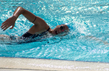 Μια γυναίκα κολυμπάει σε πισίνα. 