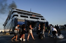 Πολίτες με βαλίτσες ετοιμάζονται για την επιβίβασή του σε πλοίο στο λιμάνι του Πειραιά