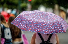 Γυναίκα κρατά ομπρέλα σε καλοκαιρινή βροχή