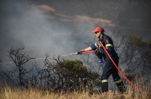 Πυροσβέστης με τη μάνικα ανά χείρας επιχειρεί για την κατάσβεσης φωτιάς