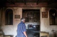 Πολίτης μπαίνει στο σπίτι του που έχει υποστεί καταστροφές από τις φλόγες στην Αγία Παρασκευή