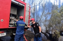 Πυροσβέστες πίσω από όχημα σε περιοχή όπου έχει ξεσπάσει πυρκαγιά - Φορούν τις μάσκες προστασίας τους