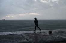 Πολίτης με αδιάβροχο τρέχει στην παραλία της Θεσσαλονίκης