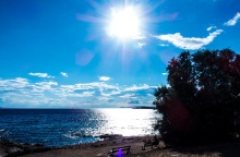 Ήλιος λαμπερός και λίγα σύννεφα πάνω από παραλία