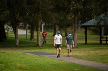 Πολίτες με μάσκα προστασίας και αθλητικά ρούχα απολαμβάνουν τις βόλτες τους σε πάρκο στην Αυστραλία