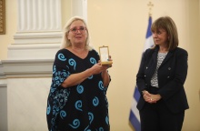 Η Μαρία Τσιαλέρα κρατά στα χέρια τον Αργυρό Σταυρό του Τάγματος της Ευποιΐας και στέκεται συγκινημένη δίπλα στην Πρόεδρο της Δημοκρατίας, Κατερίνα Σακκελαροπούλου
