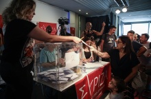 Γυναίκα με το παιδί της προσέρχονται στην κάλπη για τις εσωκομματικές εκλογές ανάδειξης νέου προέδρου στον ΣΥΡΙΖΑ