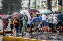 Πολίτες στο κέντρο της Αθήνας προσπαθούν να προστατευτούν από καταιγίδα