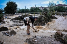 Κάτοικος του Βόλου επιχειρεί να βγάλει τη λάσπη από σημείο της πόλης