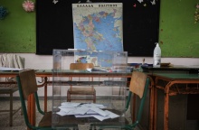 Κάλπη με ψηφοδέλτια μπροστά από χάρτη της Ελλάδας σε εκλογικό τμήμα - σχολική αίθουσα