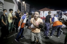 Άνδρας μεταφέρει ένα παιδί στα χέρια του στο νοσοκομείο στη Γάζα