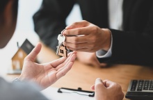 Άτομο δίνει τα κλειδιά σπιτιού σε άλλο άτομο που είναι γυρισμένο πλάτη στον φακό