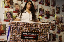 Γυναίκα κρατά πανό με τις φωτογραφίες ομήρων της Χαμάς