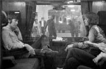 Ο Paul McCartney των Beatles και ο Mick Jagger των Rolling Stones κάθονται ο ένας απέναντι από τον άλλο σε ένα τρένο στο σταθμό Euston, περιμένοντας την αναχώρηση για το Bangor,