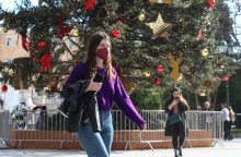Κοπέλα με μάσκα προστασίας από τον κορωνοϊό μπροστά από το χριστουγεννιάτικο δέντρο στο Σύνταγμα