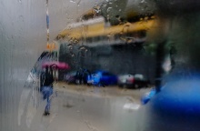 Άτομο με ομπρέλα σε λήψη από θολωμένο και βρεγμένο τζάμι