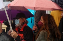 Γυναίκα με ομπρέλα φορά μάσκα δίπλα σε άνδρα επίσης με μάσκα και ομπρέλα