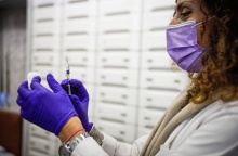 Γυναίκα κρατά εμβόλιο και βαμβάκι στα χέρια της