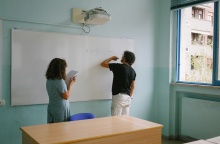 Μαθήτρια και καθηγητής σε τάξη γράφουν στον πίνακα