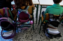 Μαθητές καθισμένοι στις καρέκλες τους και οι ανοιχτές τους τσάντες γεμάτες βιβλία