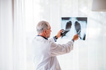 Ιατρός εξετάζει ακτινογραφία στην οποία διακρίνονται οι πνεύμονες