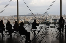 Συννεφιά και άτομα που κάθονται σε τραπεζάκια στο Κέντρο Πολιτισμού Ίδρυμα Σταύρος Νιάρχος