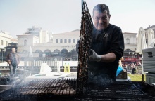 Ψήστης γυρνά τις σχάρες με τα κοψίδια σε υπαίθριο ψήσιμο την Τσικνοπέμπτη