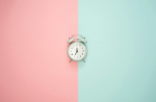 Ρολόι στη μέση ενός τοίχου που είναι μισός βαμένος ροζ, μισός βαμμένος πράσινος