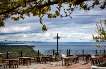 Συννεφιασμένος καιρός και υπαίθρια ταβέρνα με τραπεζάκια σε μπαλκόνι με θέα