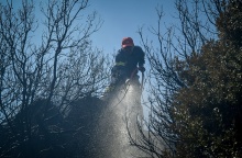 Πυροσβέστης με τη μάνικα ανά χείρας κατά την κατάσβεση φωτιάς