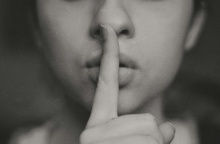 Γυναίκα κρατά το δάχτυλό της μπροστά από το κλειστό στόμα της ζητώντας ησυχία