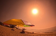 Ομπρέλα σε παραλία και λουόμενοι υπό τον καυτό ήλιο