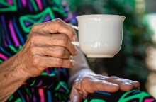 Τα χέρια ηλικιωμένης γυναίκας με φλιτζάνι καφέ