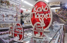 Διακοσμητικά που γράφουν «Καλό Πάσχα» σε κατάστημα με λαμπάδες και άλλα πασχαλινά προϊόντα