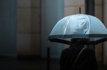 Γυναίκα κρατάει ομπρέλα μέσα στη βροχή