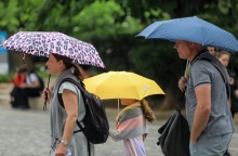 Ζευγάρι με το παιδί τους κρατούν ομπρέλες για να προστατευτούν από τη βροχή