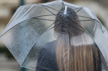 Γυναίκα κρατά ομπρέλα για να προστατευτεί από τη βροχή