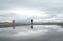 Γυναίκα στέκεται στην παραλία της Θεσσαλονίκης με συννεφιασμένο καιρό