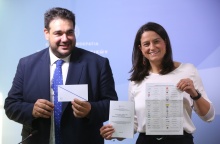 Η Νίκη Κεραμέως και ο Θοδωρής Λιβάνιος κρατούν τον φάκελο και το περιεχόμενό του για την επιστολική ψήφο