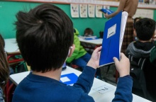 Μαθητής κρατά βιβλίο ενώ κάθεται στη θέση του στην τάξη 